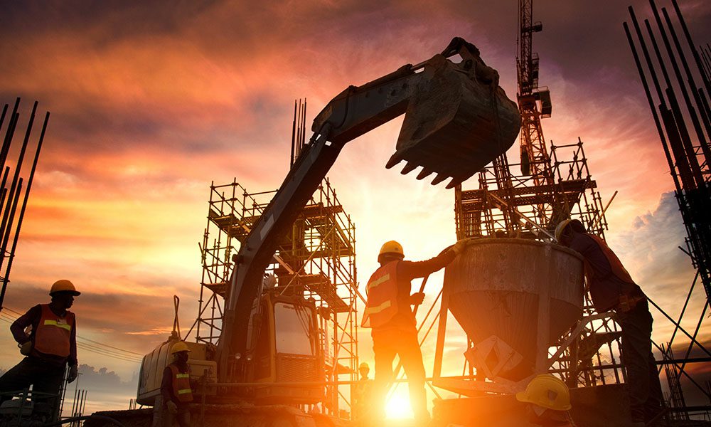 Blog - Construction Workers at the Work Site Using Equipment for Cement and a Large Crane Machine During Sunset on a Nice Day