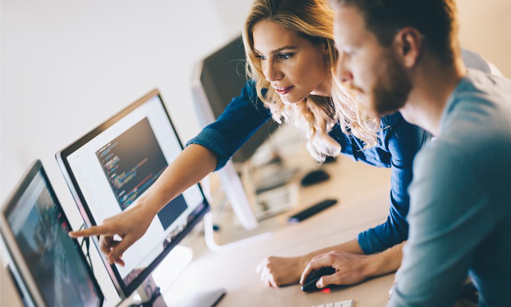 Blog Post - Programmers Working While Pointing and Discussing in Front of Computers